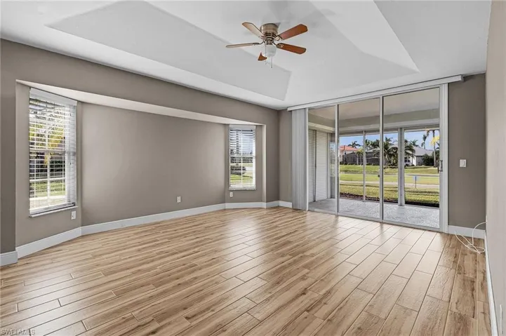 Spare room with light hardwood / wood-style floors, a raised ceiling, and ceiling fan