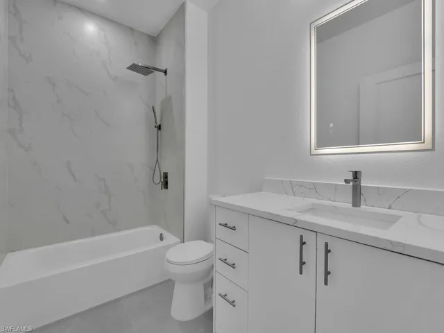 Bathroom featuring vanity, a combined bath / shower with marble appearance, and light tile patterned floors