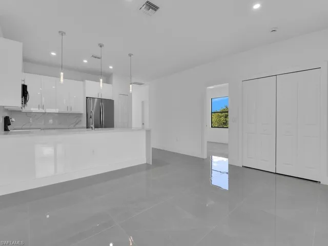 Kitchen with white cabinets, light stone countertops, a peninsula, pendant lighting, and recessed lighting