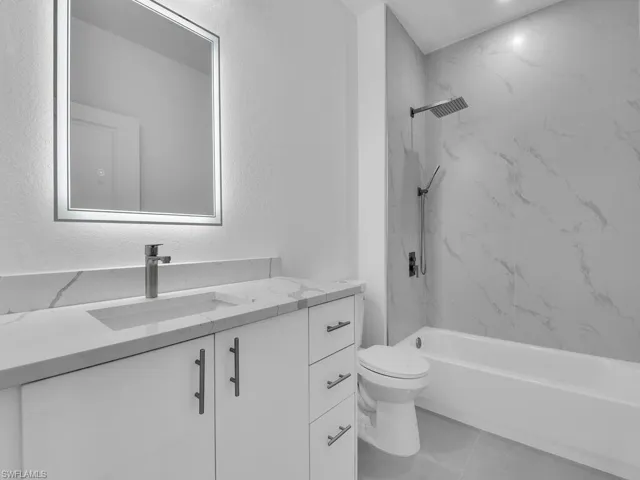 Bathroom with vanity, tile patterned flooring, a combined bath / shower with marble appearance, and a textured wall