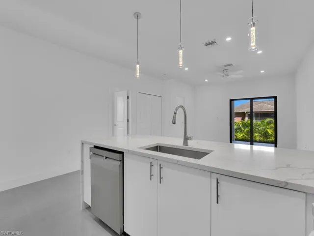 Kitchen with light stone counters, hanging light fixtures, recessed lighting, stainless steel dishwasher, and a ceiling fan