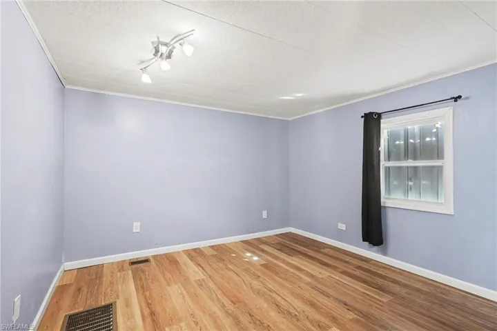 Empty room featuring light wood-style flooring, crown molding, and a textured ceiling
