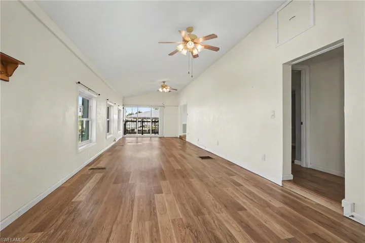 Unfurnished living room featuring vaulted ceiling, dark wood-type flooring, and ceiling fan