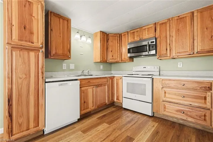 Kitchen with white appliances, light countertops, and light wood-style flooring