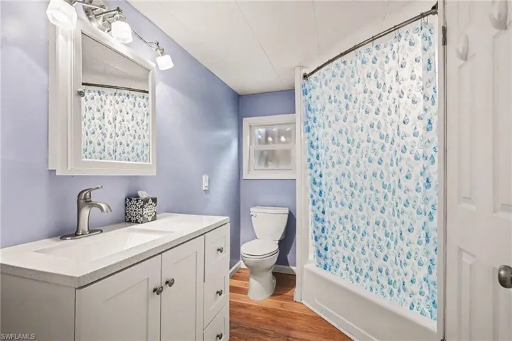Bathroom with vanity, light wood-type flooring, and shower / bath combination with curtain