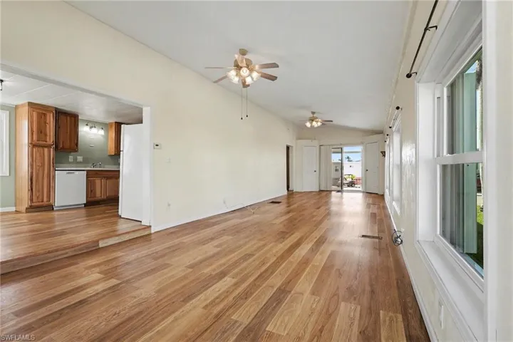 Unfurnished living room featuring vaulted ceiling, light wood-style flooring, and ceiling fan