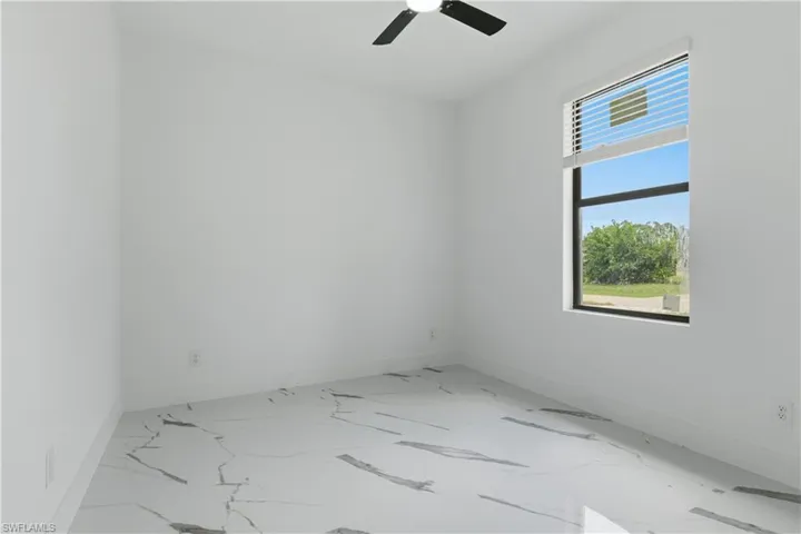 Room featuring a large window, white walls, and a ceiling fan
