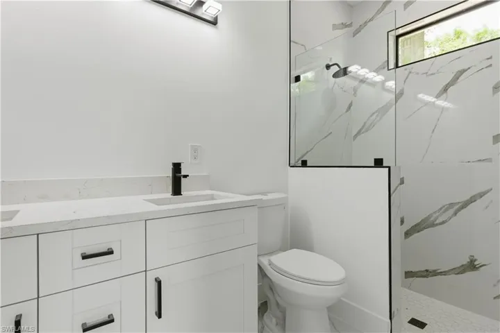 Modern bathroom featuring a double vanity with white cabinetry and matte black hardware, a sleek black faucet, and an integrated rectangular sink