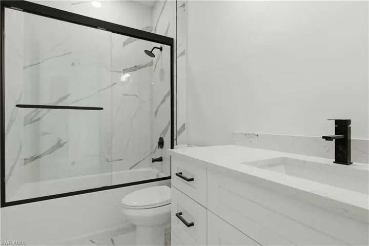 Modern bathroom featuring a white vanity with integrated sink, matte black faucet, and a quartz-finish countertop