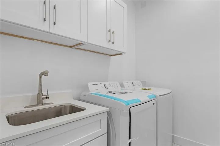Laundry area with washing machine and clothes dryer, sink, and cabinets