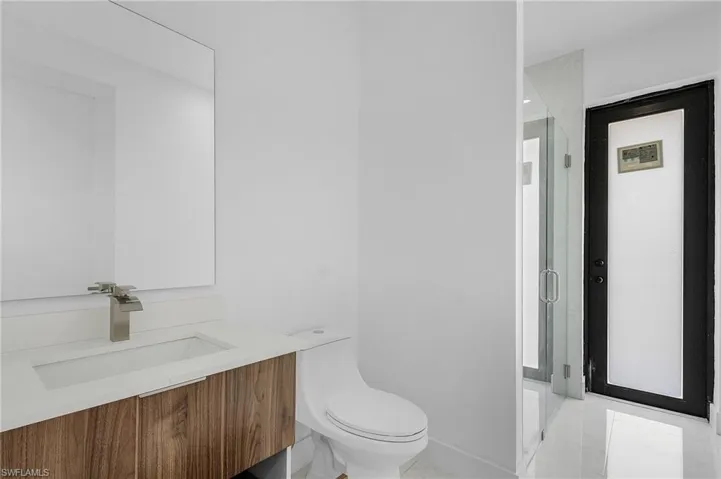 Bathroom with vanity, an enclosed shower, tile patterned flooring, and toilet
