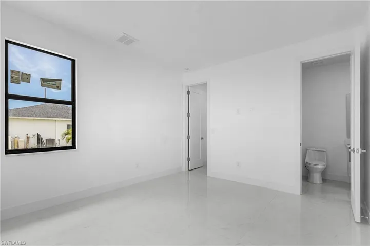 Unfurnished bedroom featuring light tile patterned flooring and ensuite bath