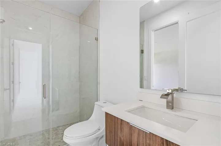 Bathroom featuring vanity, an enclosed shower, and toilet