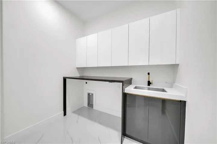 Laundry area featuring light marble finish floors and cabinet space