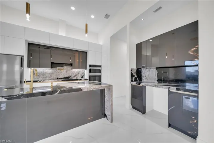 Kitchen featuring modern cabinets, backsplash, and dark stone counters