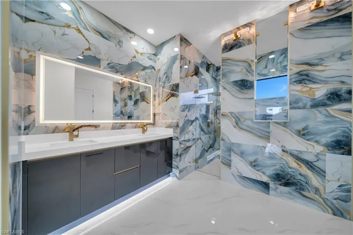 Bathroom featuring double vanity, stone wall, and recessed lighting