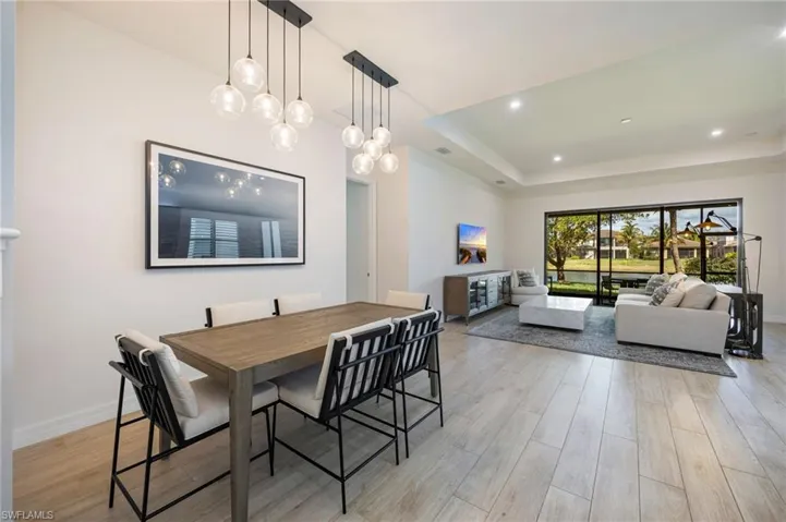 Dining area featuring light wood-type flooring, a tray ceiling, and recessed lighting