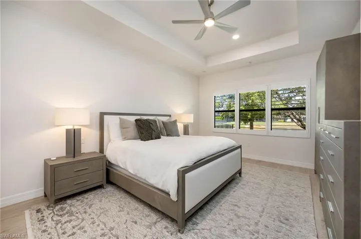 Bedroom featuring a ceiling fan, light wood-style flooring, a tray ceiling, a closet, and recessed lighting