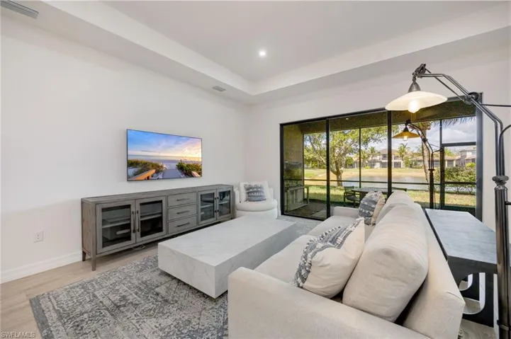 Living area with a tray ceiling, light wood finished floors, and recessed lighting