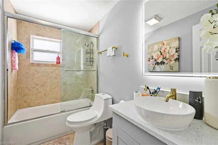 Full bathroom with vanity, enclosed tub / shower combo, and toilet