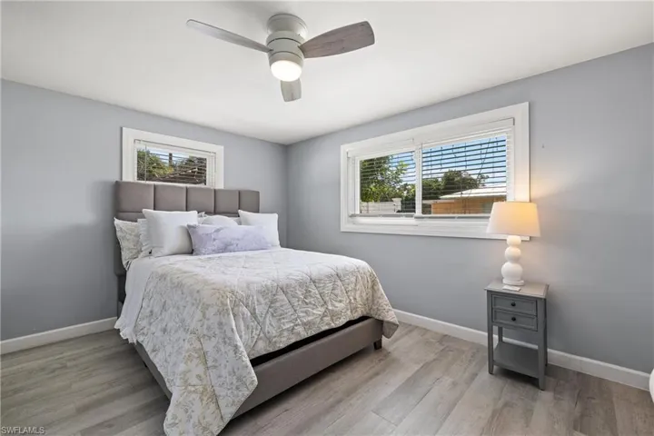 Bedroom with ceiling fan, multiple windows, and light wood-type flooring