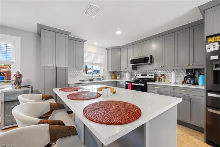 Kitchen featuring appliances with stainless steel finishes, a kitchen island, plenty of natural light, and gray cabinetry