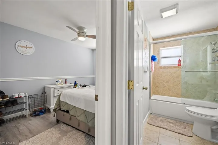 Bathroom with toilet, hardwood / wood-style floors, bath / shower combo with glass door, and ceiling fan