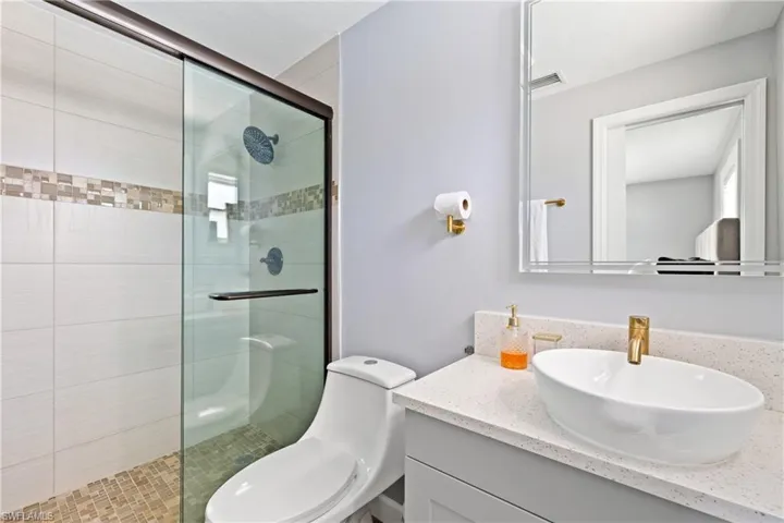 Bathroom with toilet, an enclosed shower, and vanity