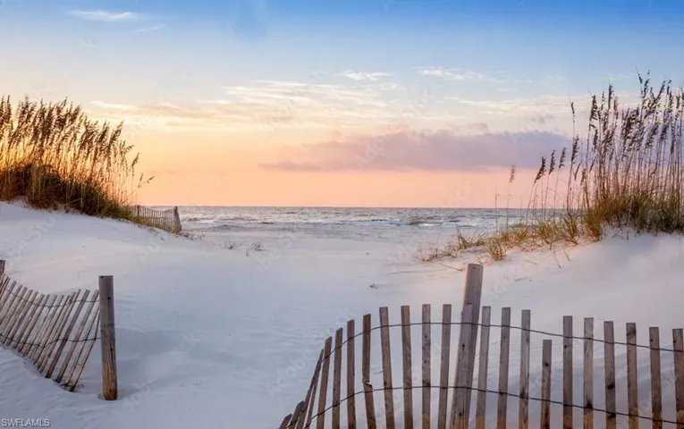 Yard at dusk with a water view, fence, and a beach view