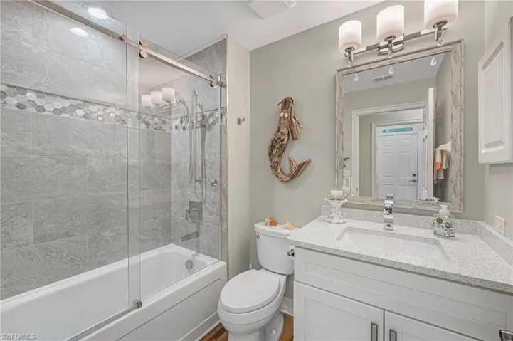 Remodeled second bath has a custom tub and glass enclosed shower combination. Quartz countertop vanity. Custom tile with beautful listello.