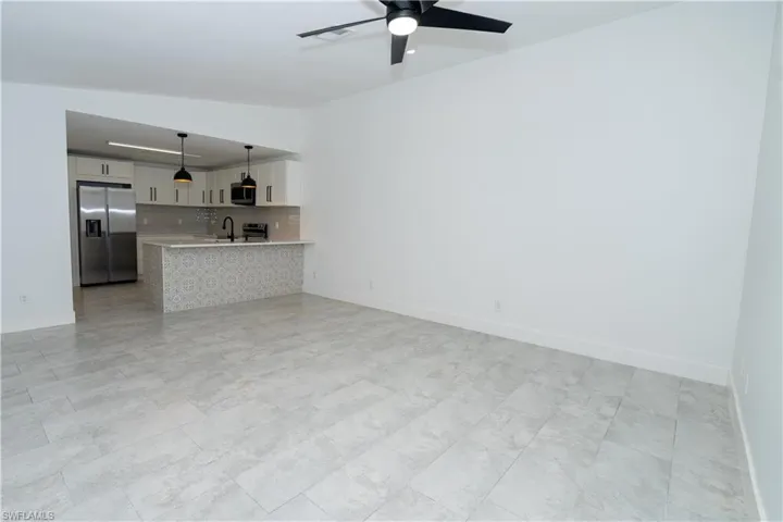 Open concept living area featuring light gray tile flooring and a ceiling fan with black blades