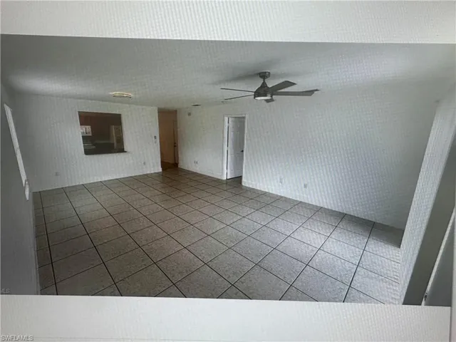 Unfurnished living room with tile patterned floors, a ceiling fan, and wallpapered walls