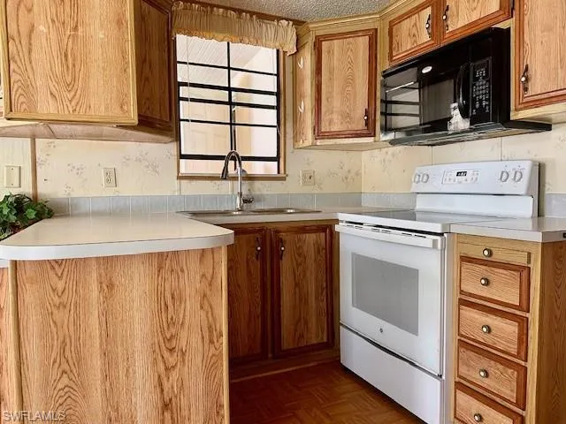 Kitchen with sink, dark parquet flooring, and white electric range