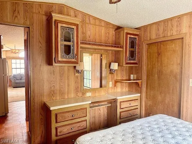 Bedroom featuring vaulted ceiling, a textured ceiling, and wood walls