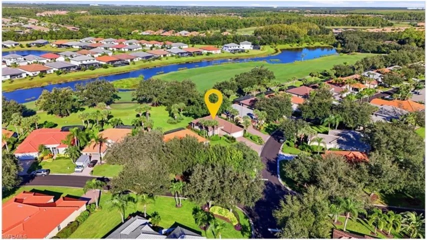 Aerial perspective of a single-family residence featuring a tiled roof, multi-car garage, mature landscaping, and proximity to golf course fairways and water features