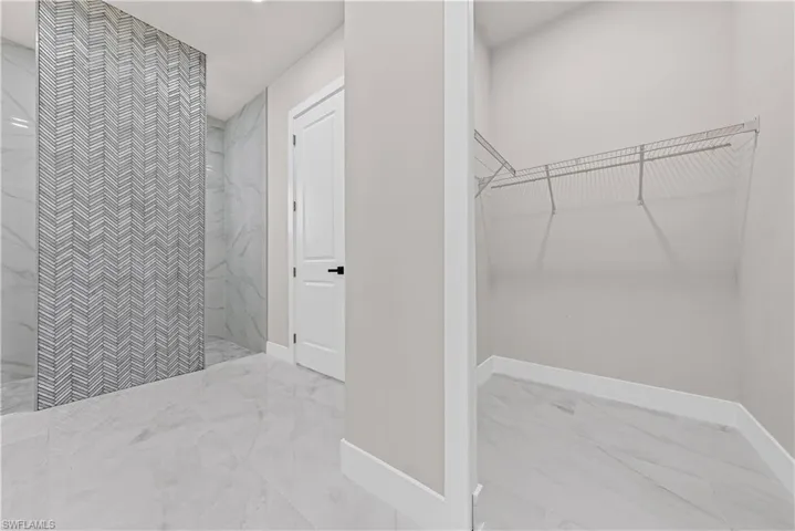Full bath with a walk in closet, light marble finish flooring, and a marble finish shower