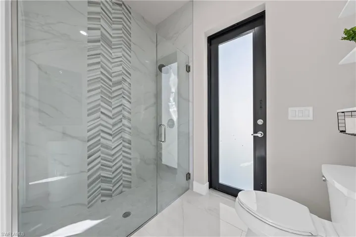 Full bath featuring light marble finish flooring and a marble finish shower