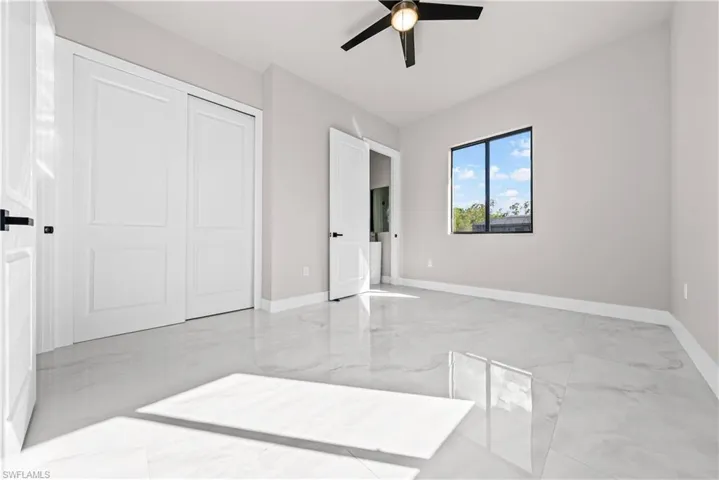 Unfurnished bedroom featuring light marble finish flooring, a ceiling fan, and a closet