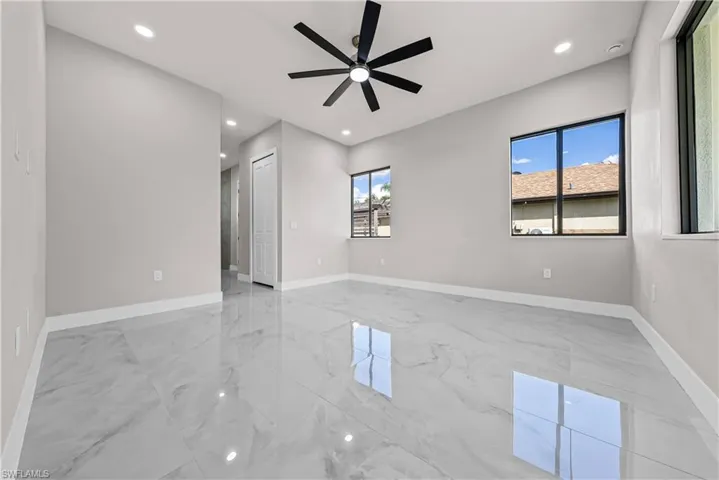 Empty room featuring ceiling fan, recessed lighting, and light marble finish flooring