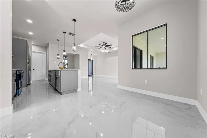 Kitchen with open floor plan, hanging light fixtures, light marble finish flooring, and gray cabinets