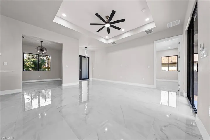 Spare room featuring ceiling fan, light marble finish flooring, healthy amount of natural light, a tray ceiling, and recessed lighting