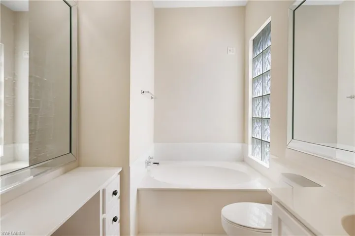 MB Bathroom featuring toilet, vanity, and a bath