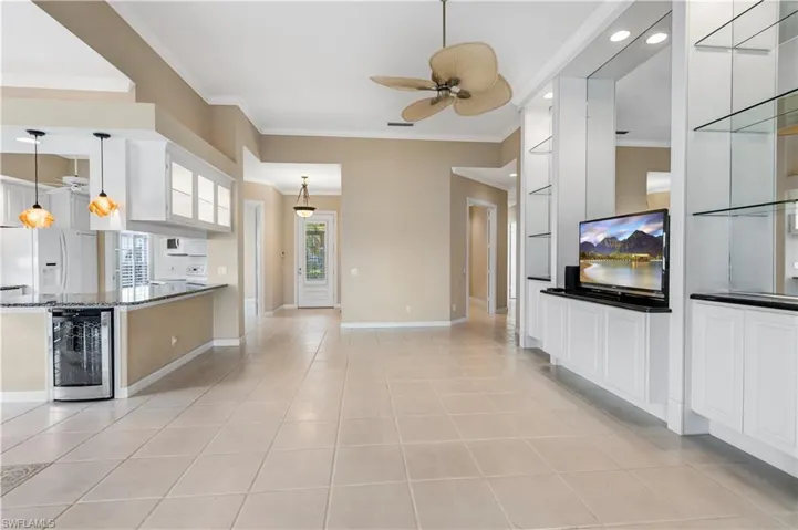 Kitchen with white refrigerator with ice dispenser, wine cooler, a ceiling fan, ornamental molding, and light tile patterned floors