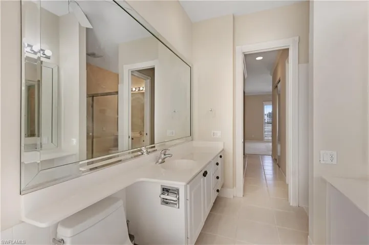 MB featuring tile patterned floors, vanity, toilet, baseboards, and a shower with door