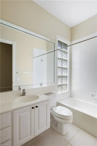Guest Bathroom with vanity, toilet, shower / bathtub combination, and tile patterned floorsAnd Glass Block wall
