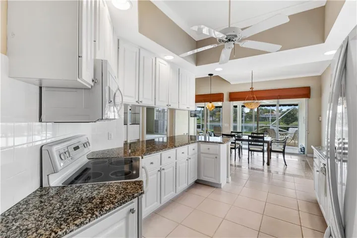 Kitchen with backsplash, a peninsula, white appliances, white cabinets, and recessed lighting