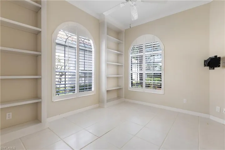 Tiled spare room with built in shelves, crown molding, baseboards, and ceiling fan