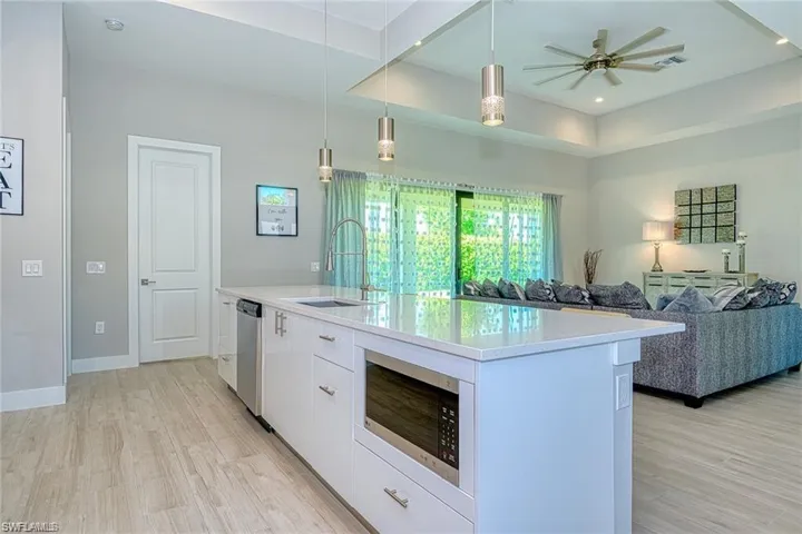 Kitchen with sink, stainless steel appliances, decorative light fixtures, a center island with sink, and white cabinets