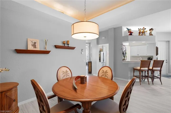 Open-concept dining area featuring light-toned wood-finish flooring and a central drum pendant light