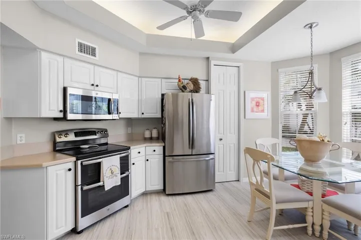 Contemporary kitchen featuring white cabinetry, stainless steel appliances, light-toned countertops, and wood-finish flooring